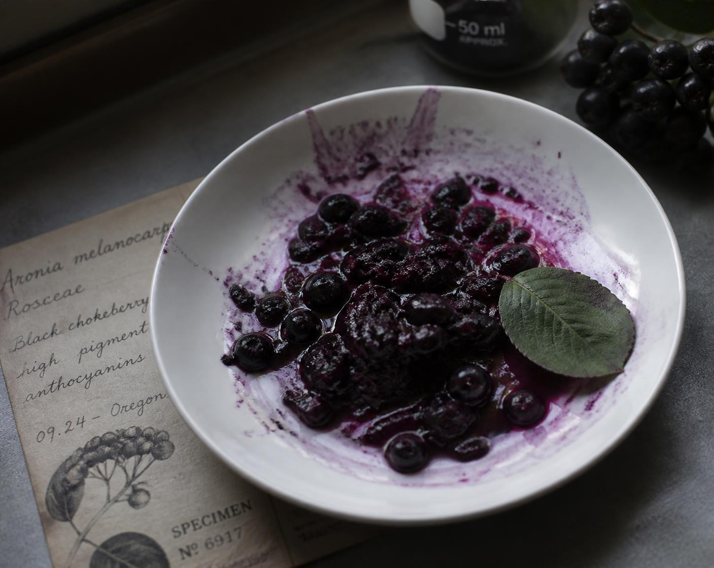 Crushed Aronia berries staining a white dish deep violet